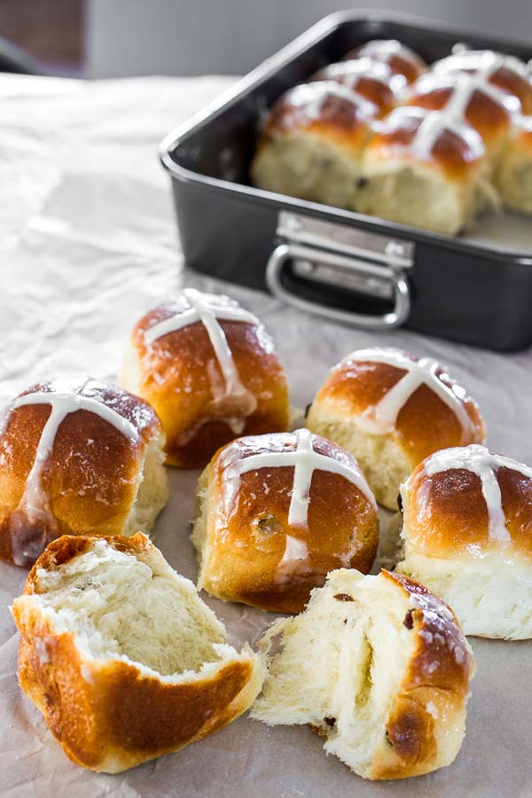 Traditional hot cross buns with cream cheese icing, brushed with sweet syrup and filled with raisins